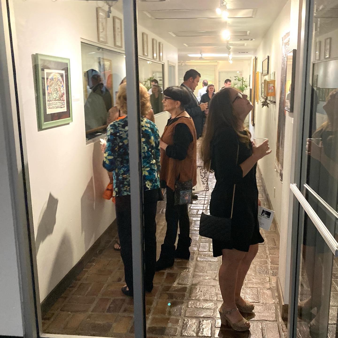 Guests viewing framed artwork along the ArtWalk gallery hallway